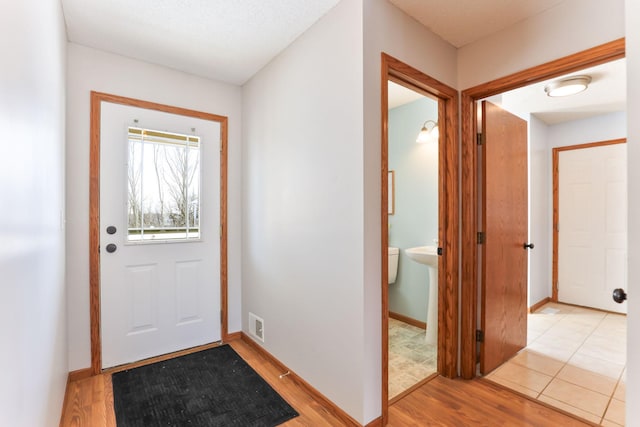 entryway featuring light wood finished floors, visible vents, and baseboards