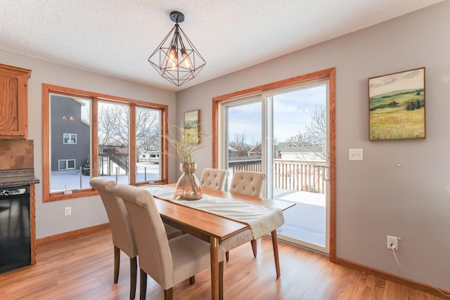 dining space featuring light wood-type flooring, plenty of natural light, and a textured ceiling