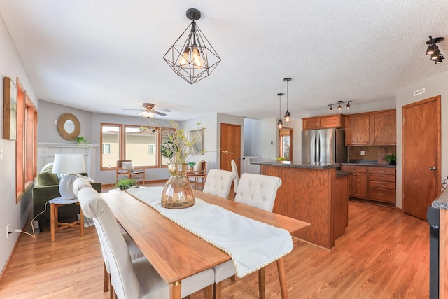 dining area featuring light wood finished floors, ceiling fan, and a textured ceiling