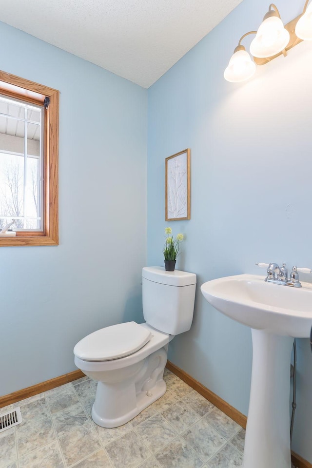 bathroom with toilet, a sink, visible vents, and baseboards