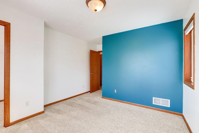 spare room with visible vents, light carpet, and baseboards