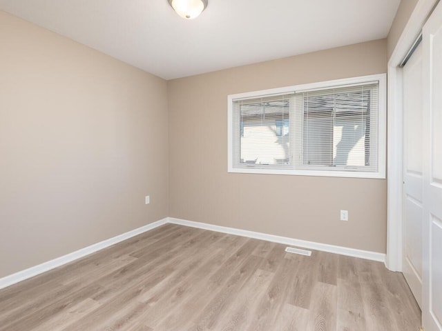 unfurnished room with light wood-type flooring, visible vents, and baseboards