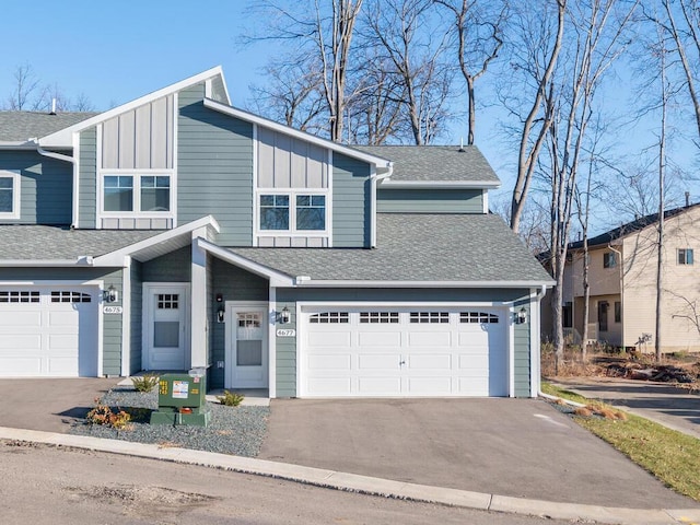 view of front facade featuring board and batten siding, an attached garage, driveway, and a shingled roof