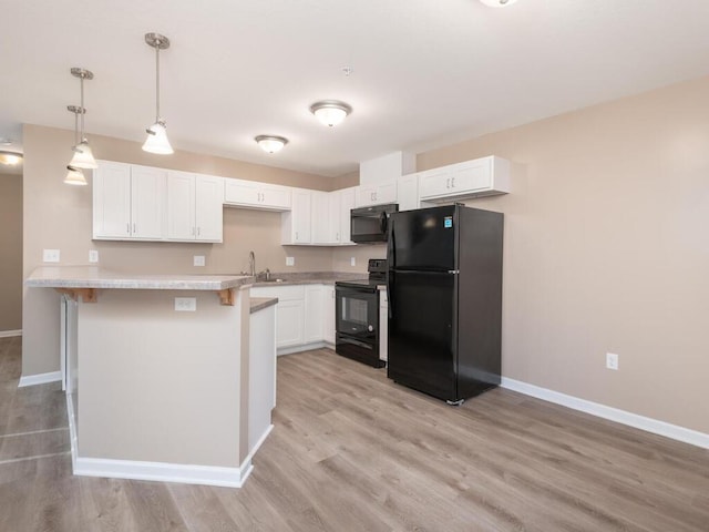 kitchen with light countertops, white cabinets, black appliances, a peninsula, and a kitchen bar