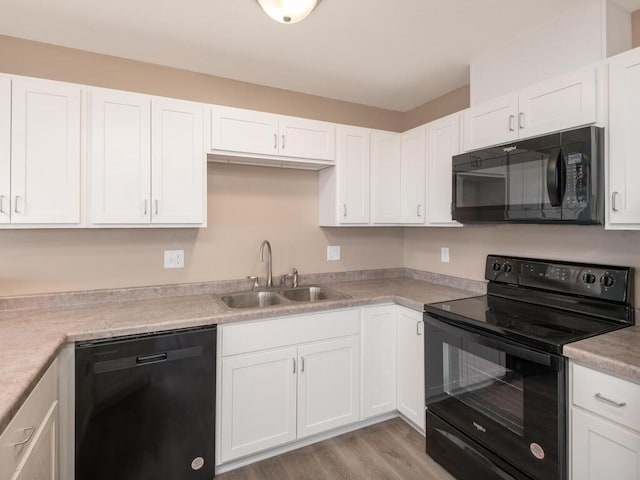 kitchen featuring black appliances, white cabinetry, light countertops, and a sink