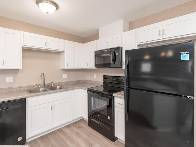 kitchen with white cabinets, light countertops, a sink, and black appliances