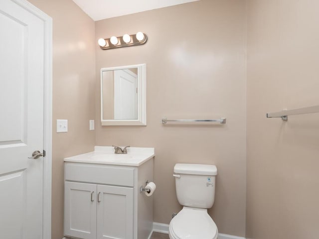 bathroom with toilet, vanity, and baseboards