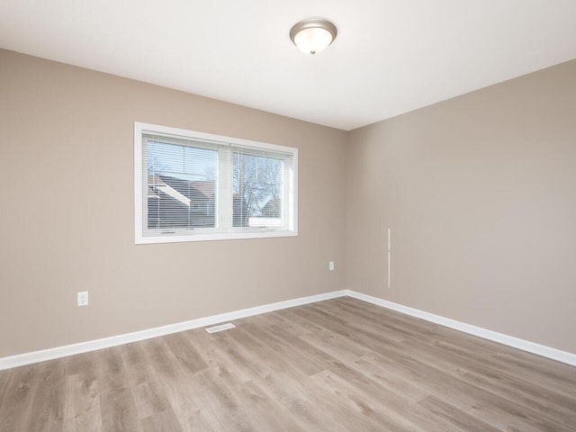 spare room with light wood-style flooring, visible vents, and baseboards