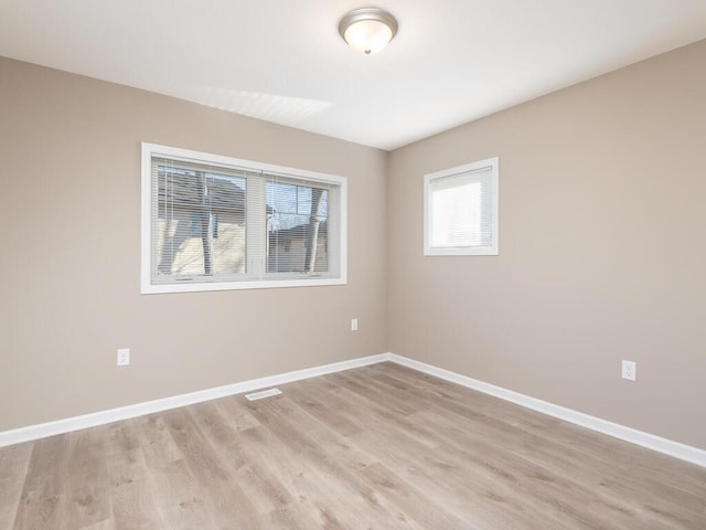 spare room with visible vents, light wood finished floors, and baseboards