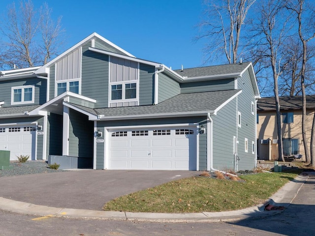 view of front facade with a garage, roof with shingles, aphalt driveway, and board and batten siding