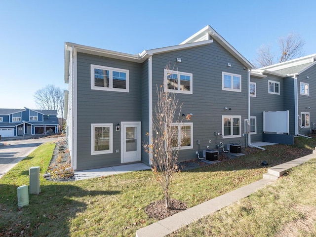 rear view of house with a yard, central AC unit, and a residential view