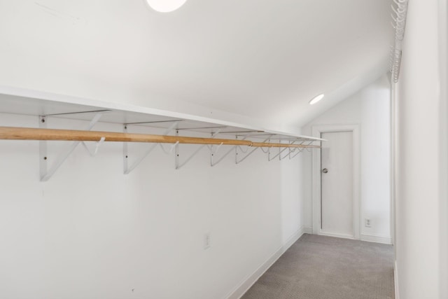 walk in closet featuring light carpet and lofted ceiling