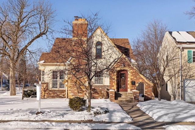 tudor home with a chimney and brick siding