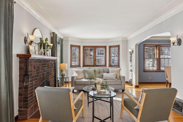 living room with arched walkways, crown molding, visible vents, light wood-style floors, and a brick fireplace