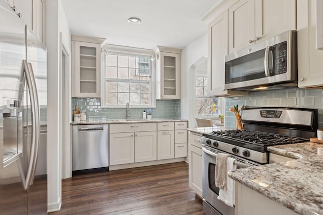 kitchen featuring stainless steel appliances, a sink, glass insert cabinets, and white cabinetry