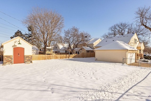 yard covered in snow featuring an outbuilding, fence, and a residential view