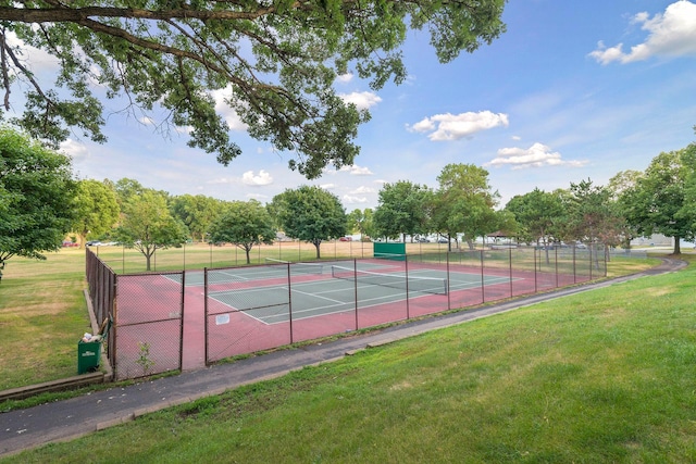 view of tennis court featuring a lawn and fence