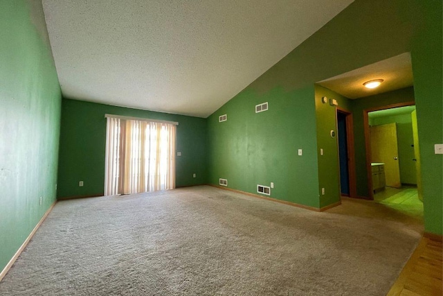 empty room featuring visible vents, vaulted ceiling, and light carpet