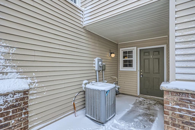 snow covered property entrance with cooling unit