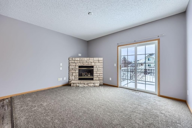 unfurnished living room with a textured ceiling, a fireplace, baseboards, and carpet flooring