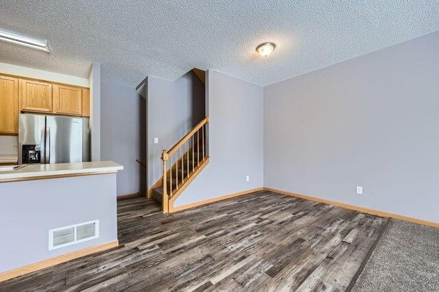 interior space featuring dark wood-style floors, light countertops, stainless steel fridge, and visible vents