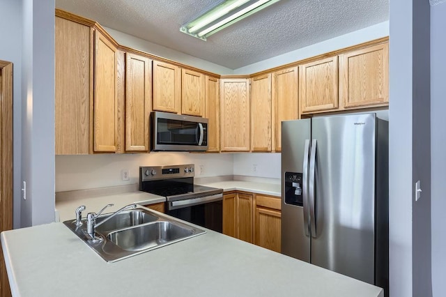 kitchen featuring appliances with stainless steel finishes, light countertops, a sink, and a textured ceiling