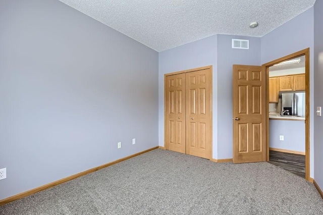 unfurnished bedroom with baseboards, visible vents, carpet floors, stainless steel refrigerator with ice dispenser, and a closet