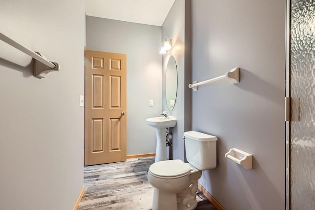 bathroom with toilet, a sink, baseboards, and wood finished floors