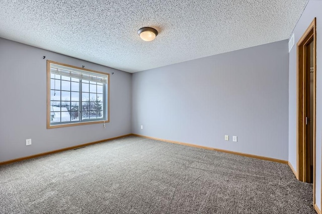 spare room featuring carpet, visible vents, baseboards, and a textured ceiling