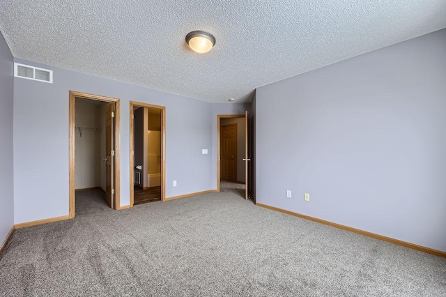 unfurnished bedroom featuring baseboards, visible vents, a spacious closet, carpet floors, and a closet