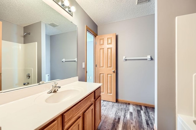 bathroom featuring visible vents, vanity, a textured ceiling, wood finished floors, and baseboards