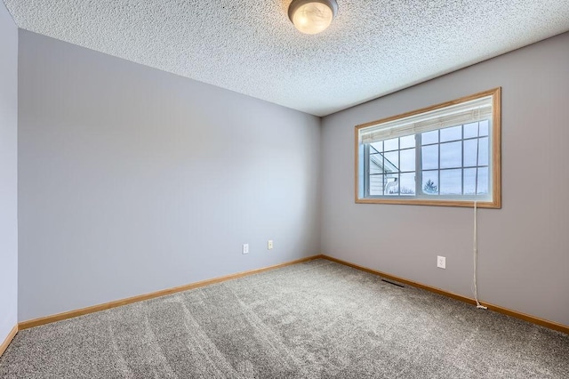 spare room with visible vents, a textured ceiling, baseboards, and carpet flooring