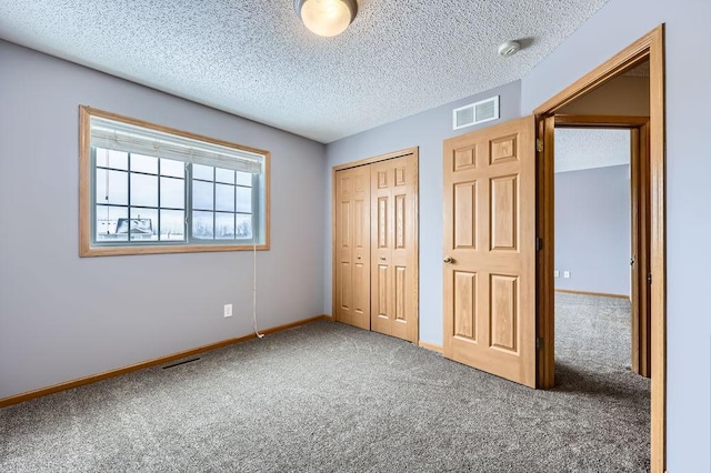 unfurnished bedroom with a textured ceiling, visible vents, baseboards, a closet, and carpet