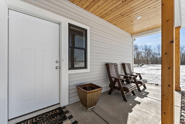 snow covered property entrance featuring covered porch