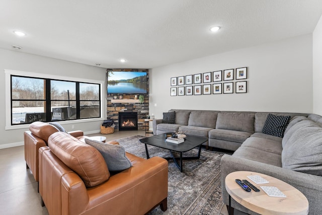 living area with baseboards, a stone fireplace, a textured ceiling, and recessed lighting