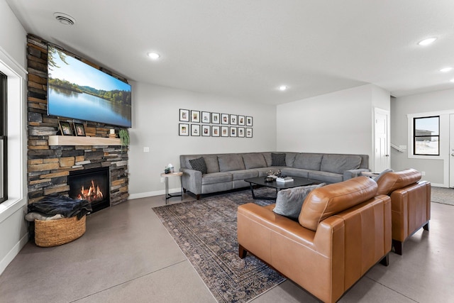 living area featuring finished concrete flooring, a fireplace, baseboards, and recessed lighting