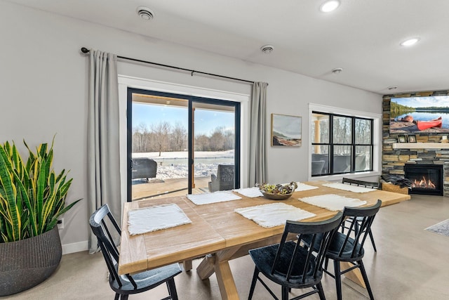 dining area with concrete flooring, a fireplace, a wealth of natural light, and recessed lighting