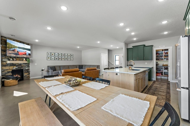 dining area with finished concrete flooring, baseboards, visible vents, a fireplace, and recessed lighting