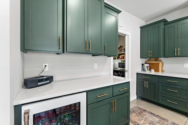 kitchen featuring green cabinets, wine cooler, stainless steel microwave, and light stone countertops