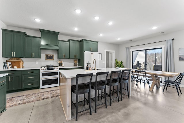 kitchen featuring green cabinets, light countertops, high end appliances, and a center island with sink