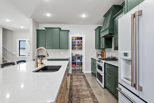 kitchen featuring a textured ceiling, premium appliances, light stone counters, a sink, and green cabinets