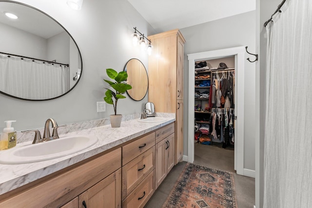 bathroom featuring a spacious closet, double vanity, and a sink