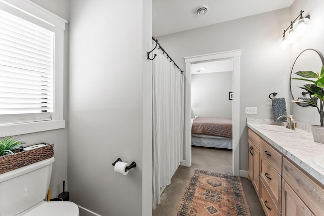 ensuite bathroom featuring concrete flooring, toilet, a sink, double vanity, and ensuite bath