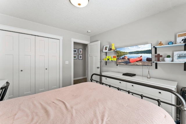 bedroom with a textured ceiling, baseboards, and a closet