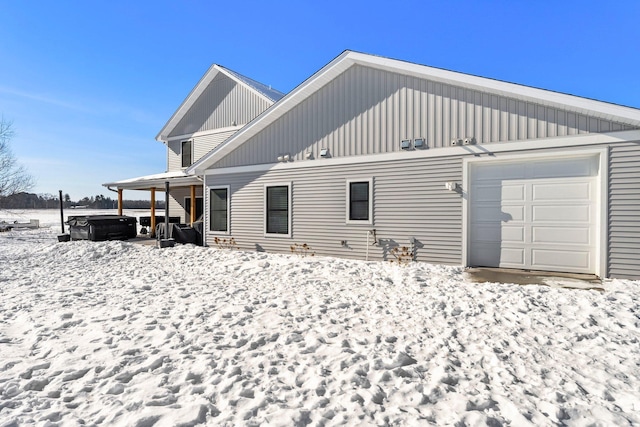 snow covered house with a garage and board and batten siding