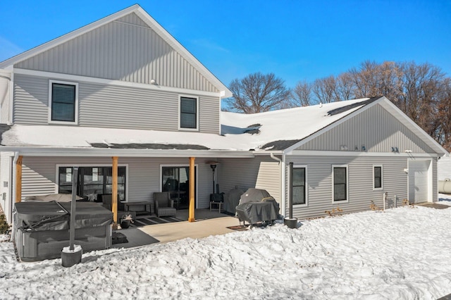 snow covered back of property with a garage