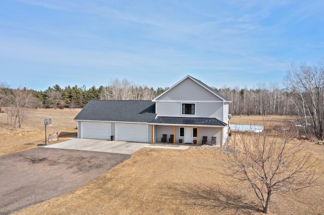 view of front of home featuring aphalt driveway, a garage, a porch, and metal roof