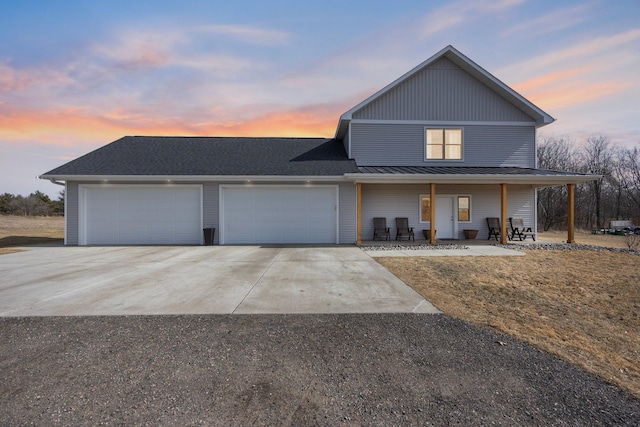 view of front of house with a standing seam roof, covered porch, concrete driveway, a garage, and metal roof