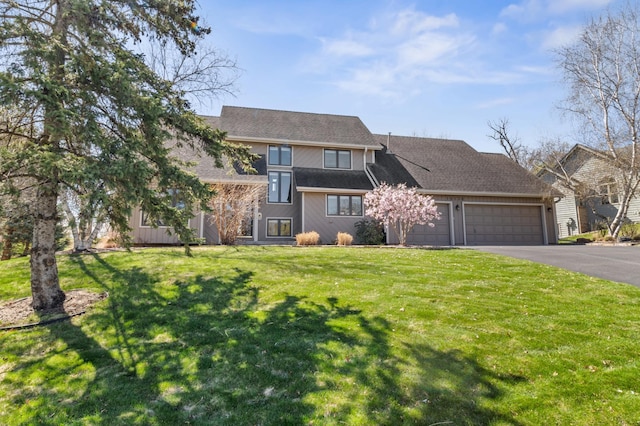 view of front of property featuring an attached garage, a front lawn, and aphalt driveway