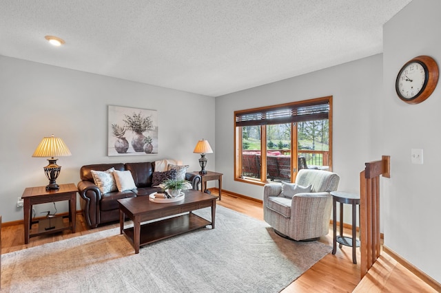 living area featuring a textured ceiling, baseboards, and light wood-type flooring